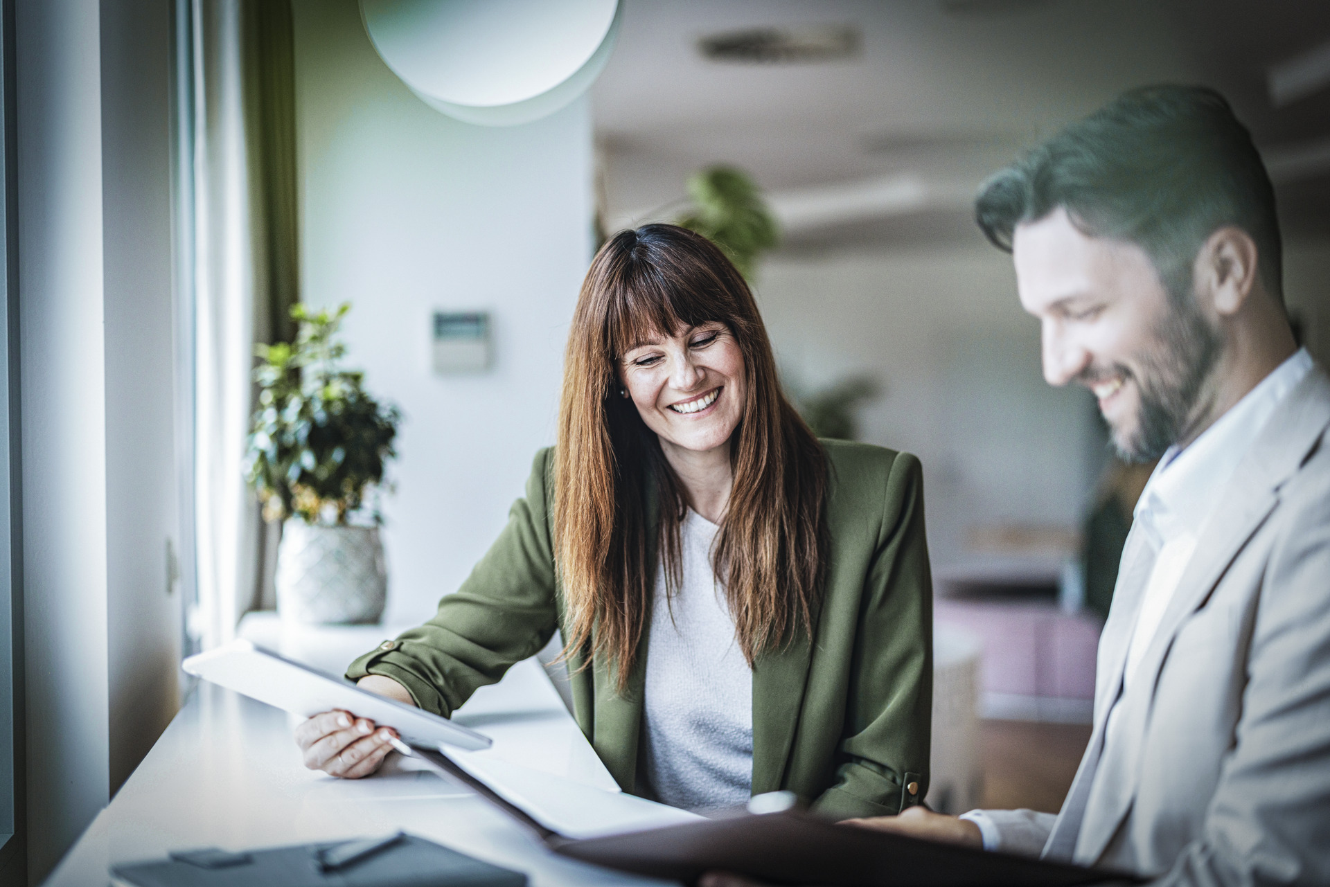 Two smiling people, a woman and a man sitting at a table.