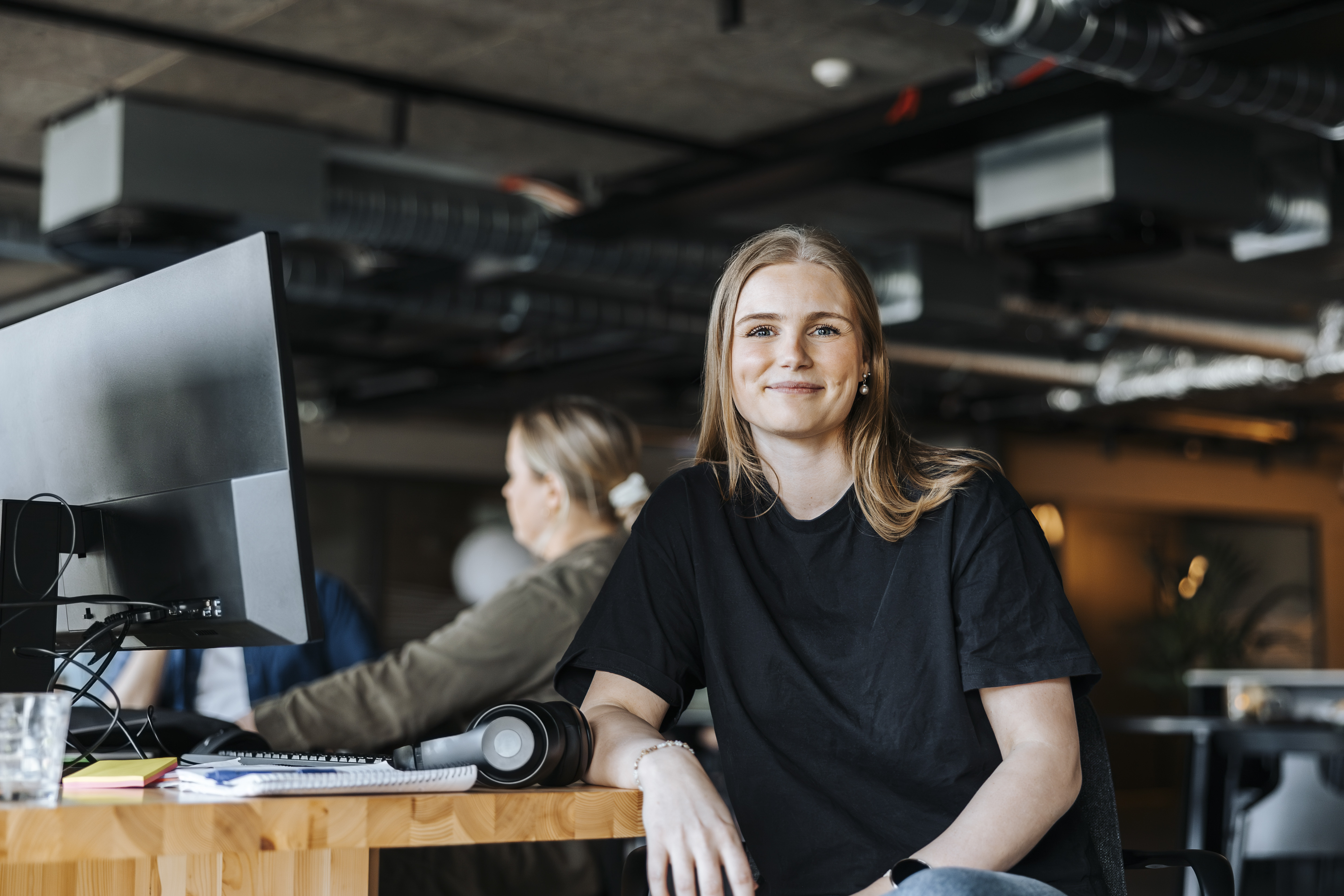 Young, smiling woman sits at her computer at work and wonders about probationary time Photo: GettyImages