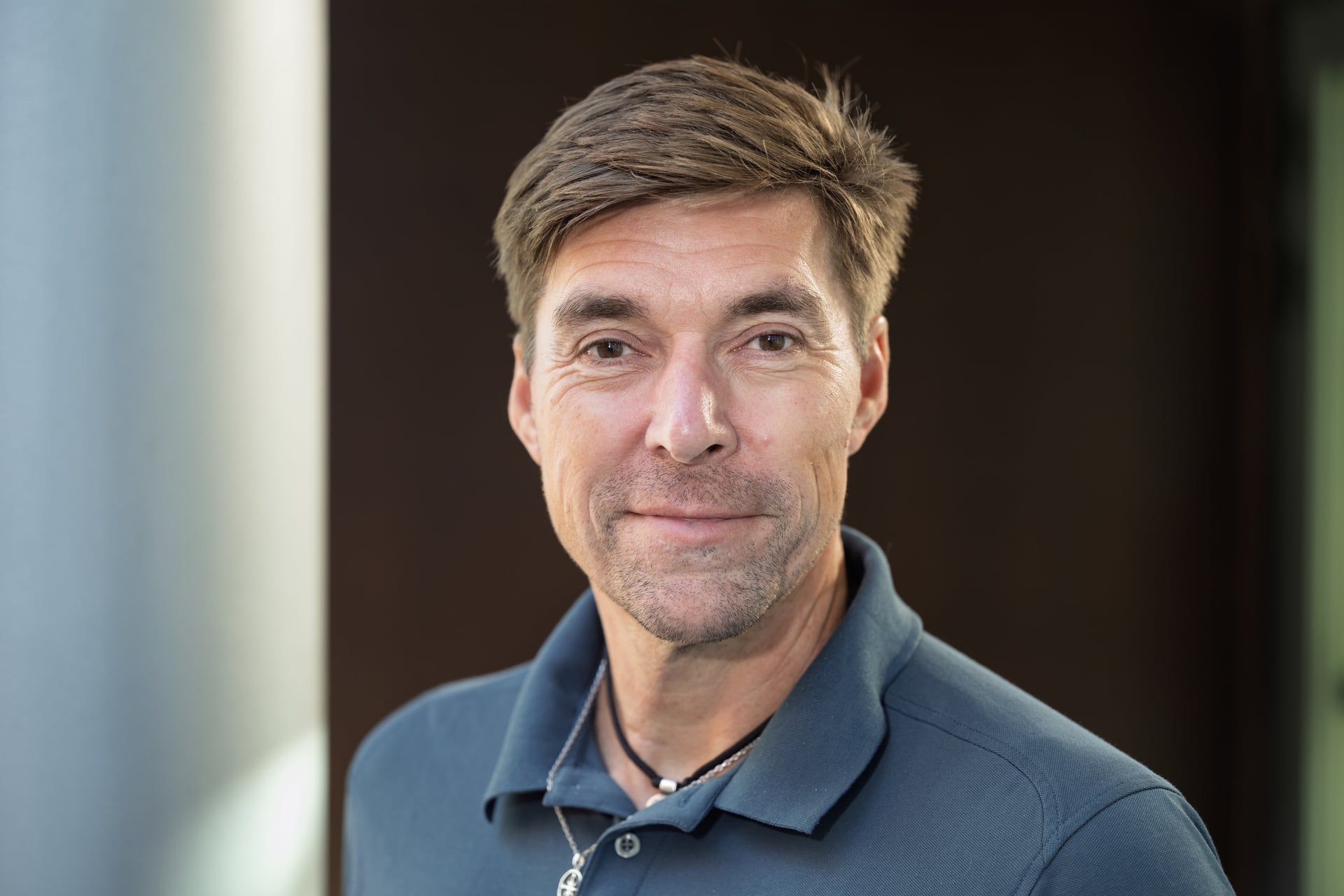 Mann med brunt hår og pique-skjorte. Nærbilde fra skuldrene opp