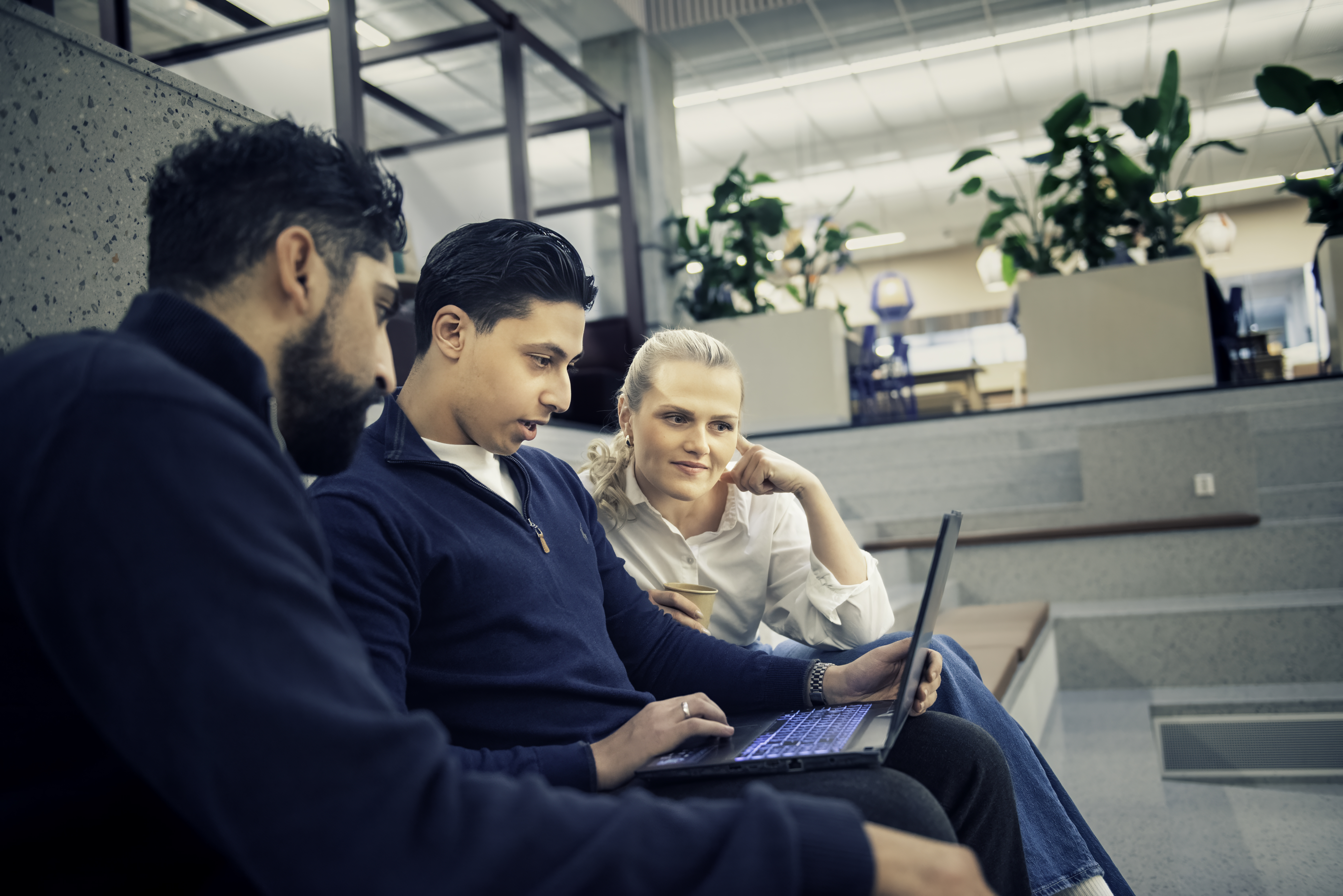 Tre studenter som ser ned på en pc