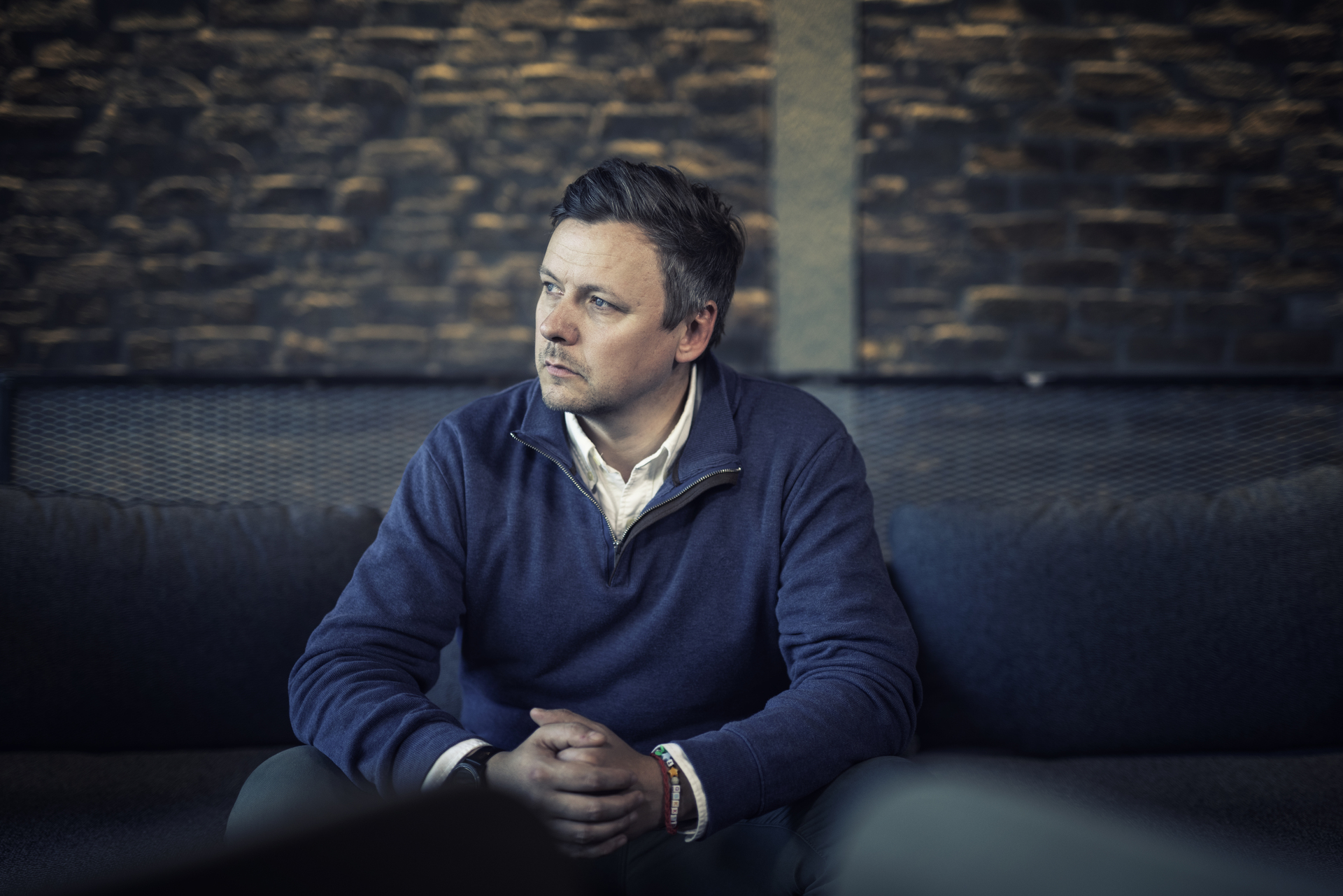 A man sits and reflects, symbolizing uncertainty and thoughts about downsizing and the future of work.