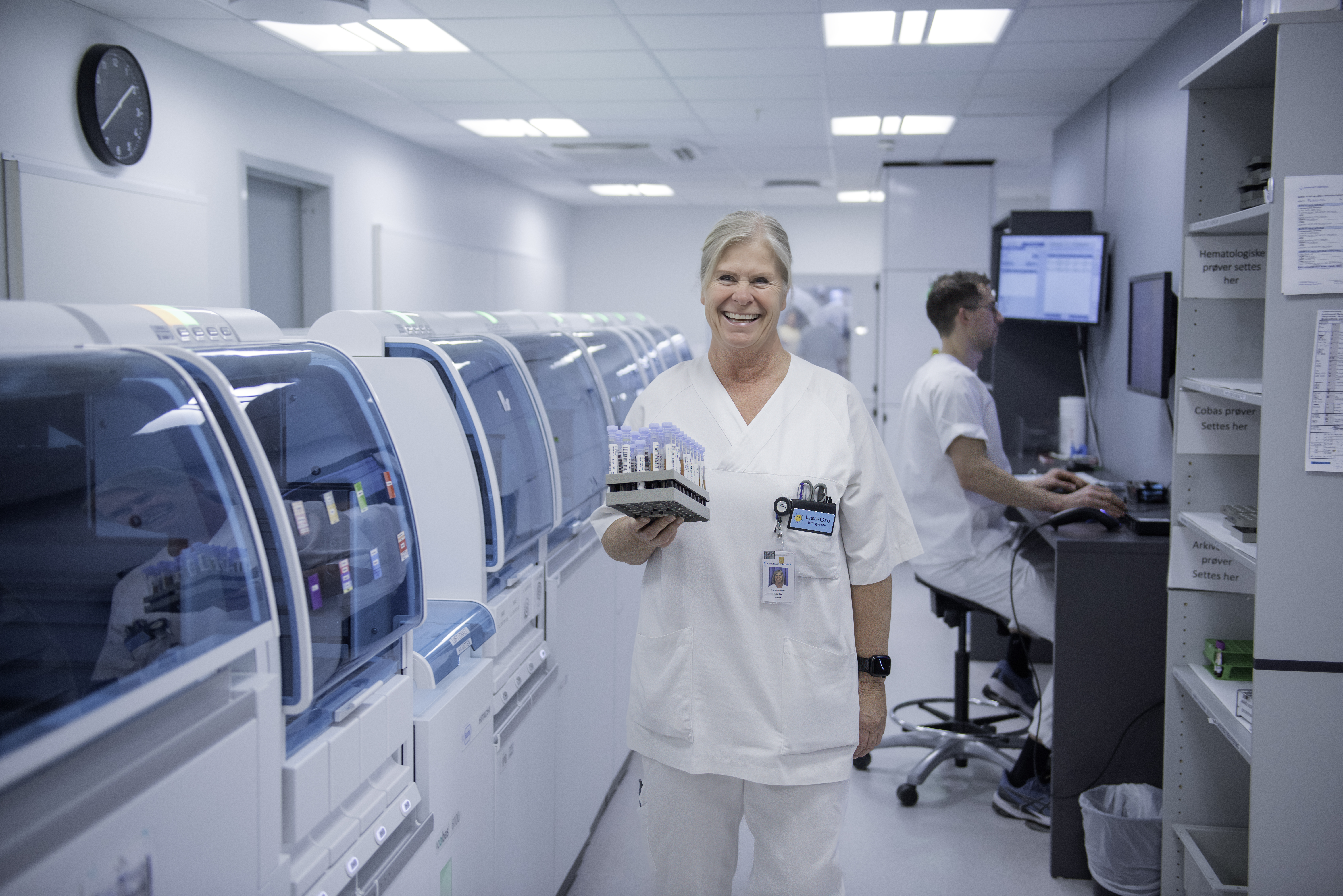  Smilende bioingeniør med blodprøver i moderne laboratoriemiljø. Kredit: Luca Kleve-Ruud