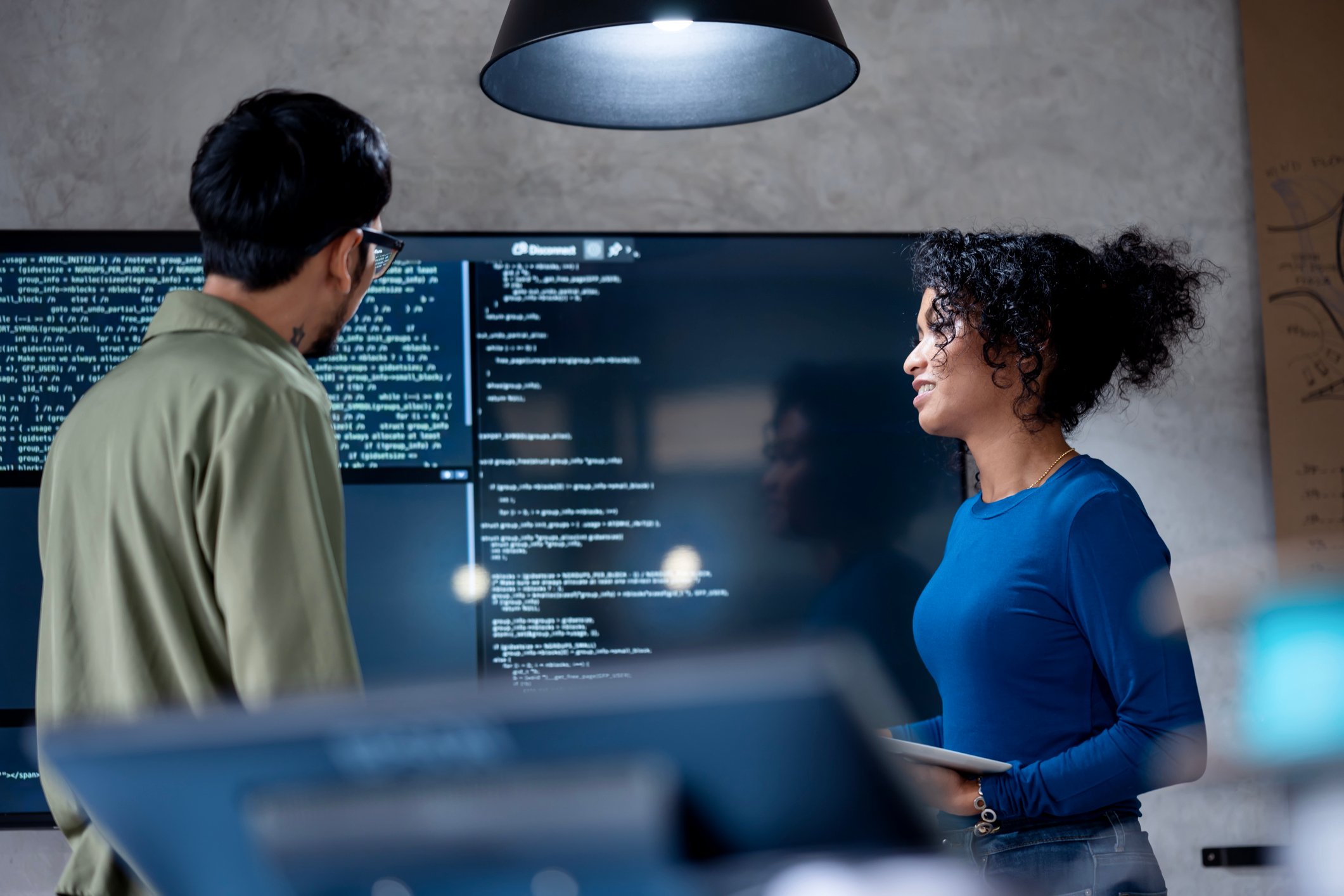 Kolleger diskuterer Python koding på en dataskjerm
