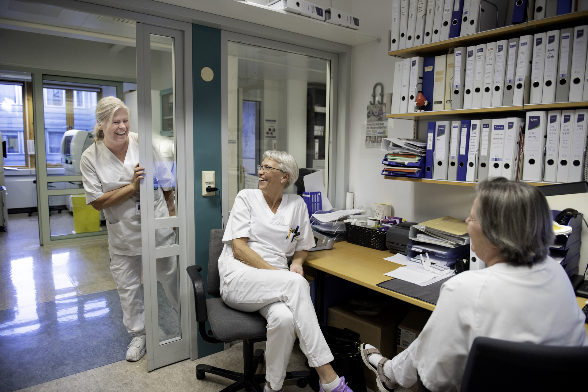 Smilende helsepersonell i et kontormiljø, symboliserer et godt arbeidsmiljø og viktigheten av tariffavtaler for ansattes trivsel og rettigheter i helsesektoren.