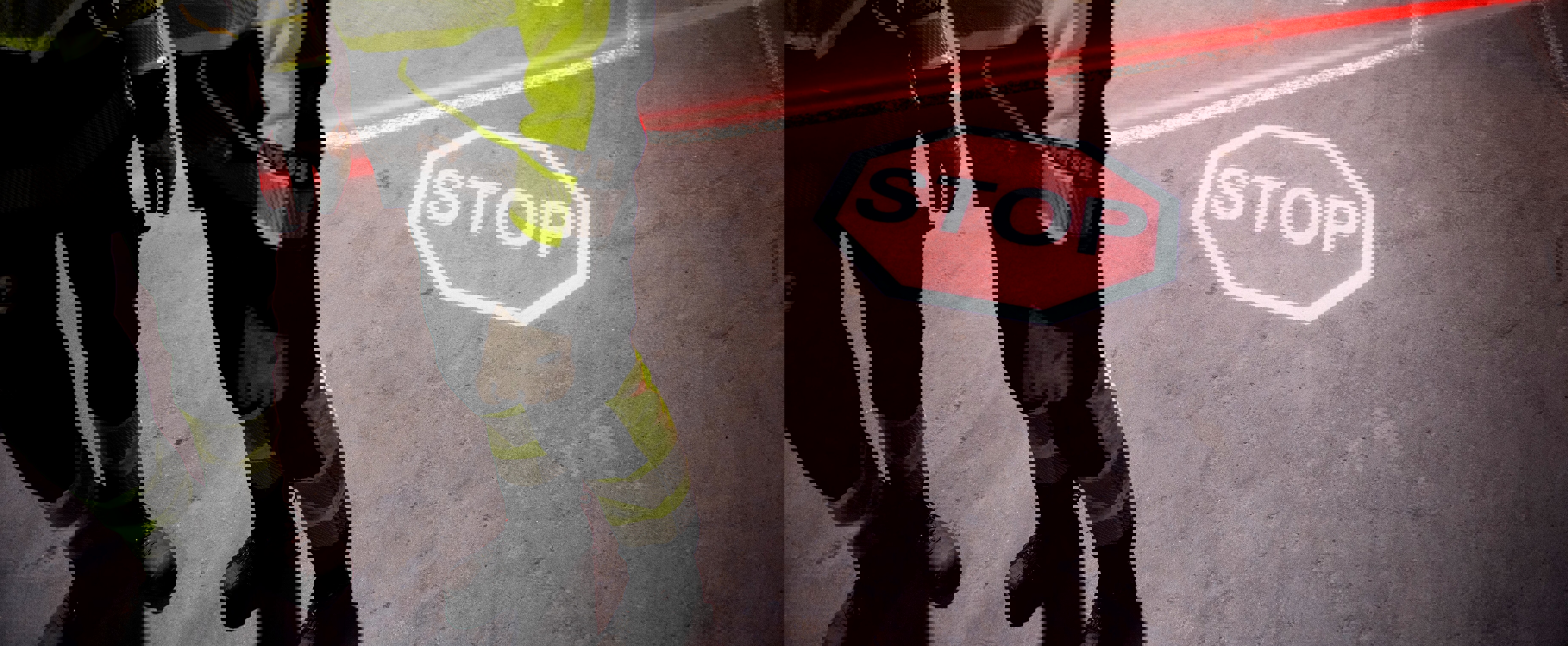 To personer med refleksvest går foran et rødt laserlys som projiserer et stoppskilt på bakken. Bildet illustrerer sikkerhetstiltak i et arbeidsområde.