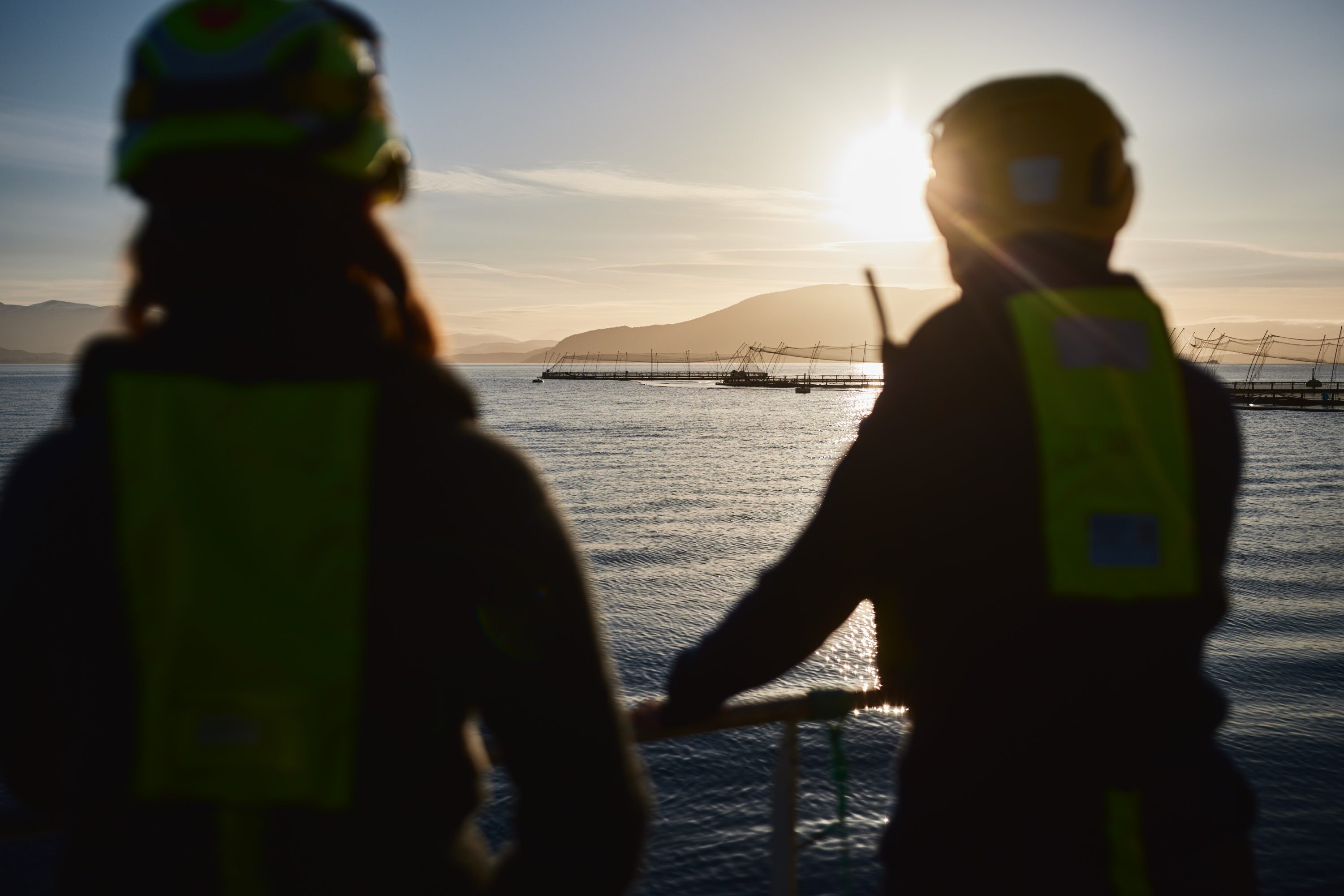 To personar som ser mot eit oppdrettsanlegg.