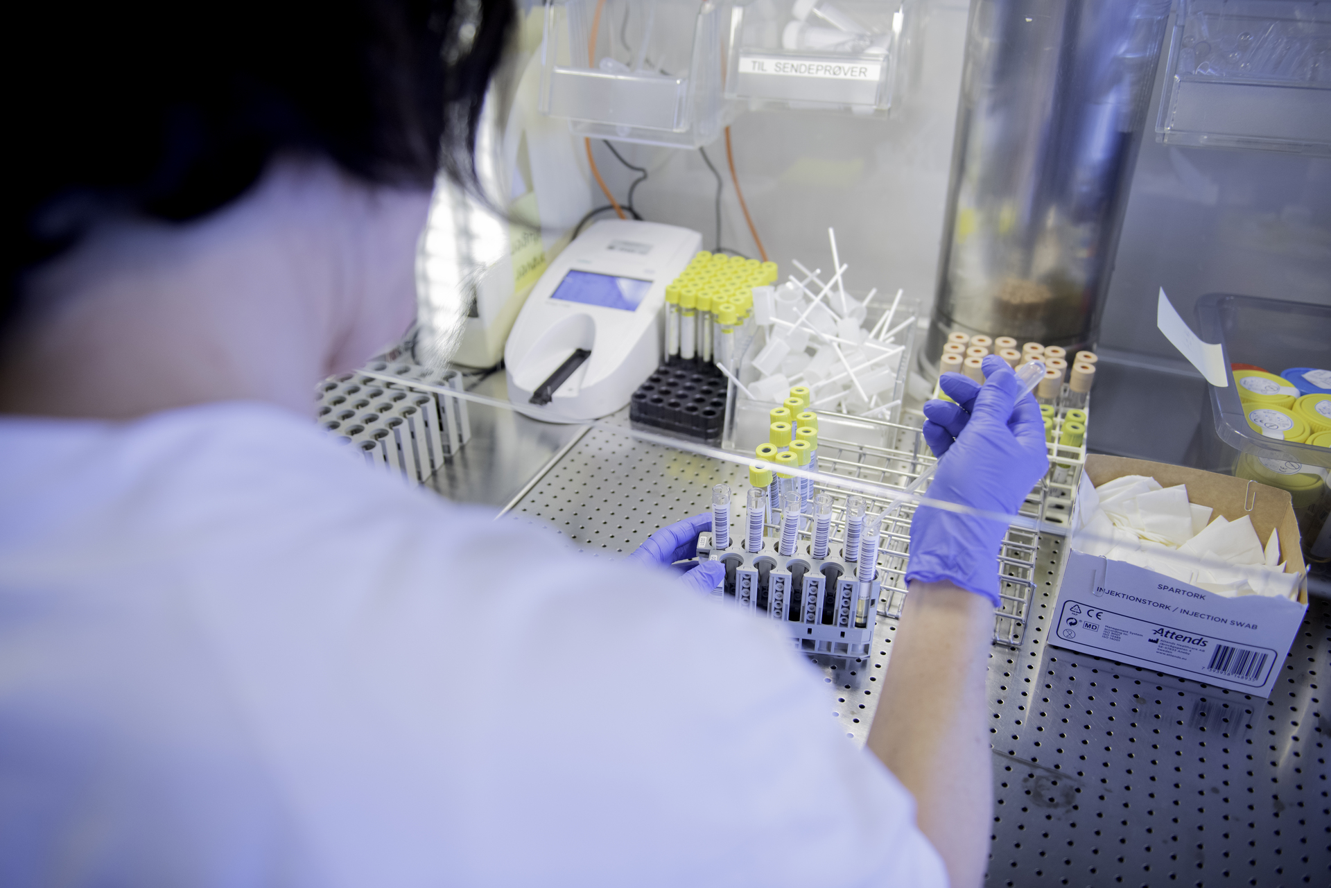 Bioingeniør jobber et laboratorium, omgitt av prøveglass og annet laboratorieutstyr.