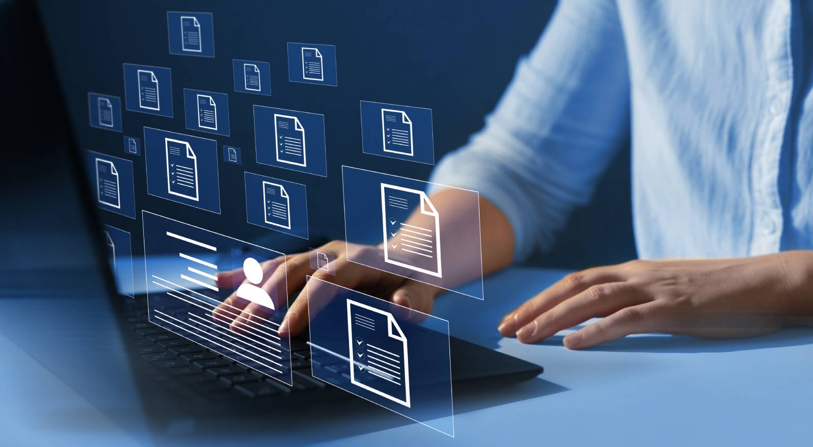 A person is typing on a laptop. Digital document icons float up from the screen – illustrating digital document management.