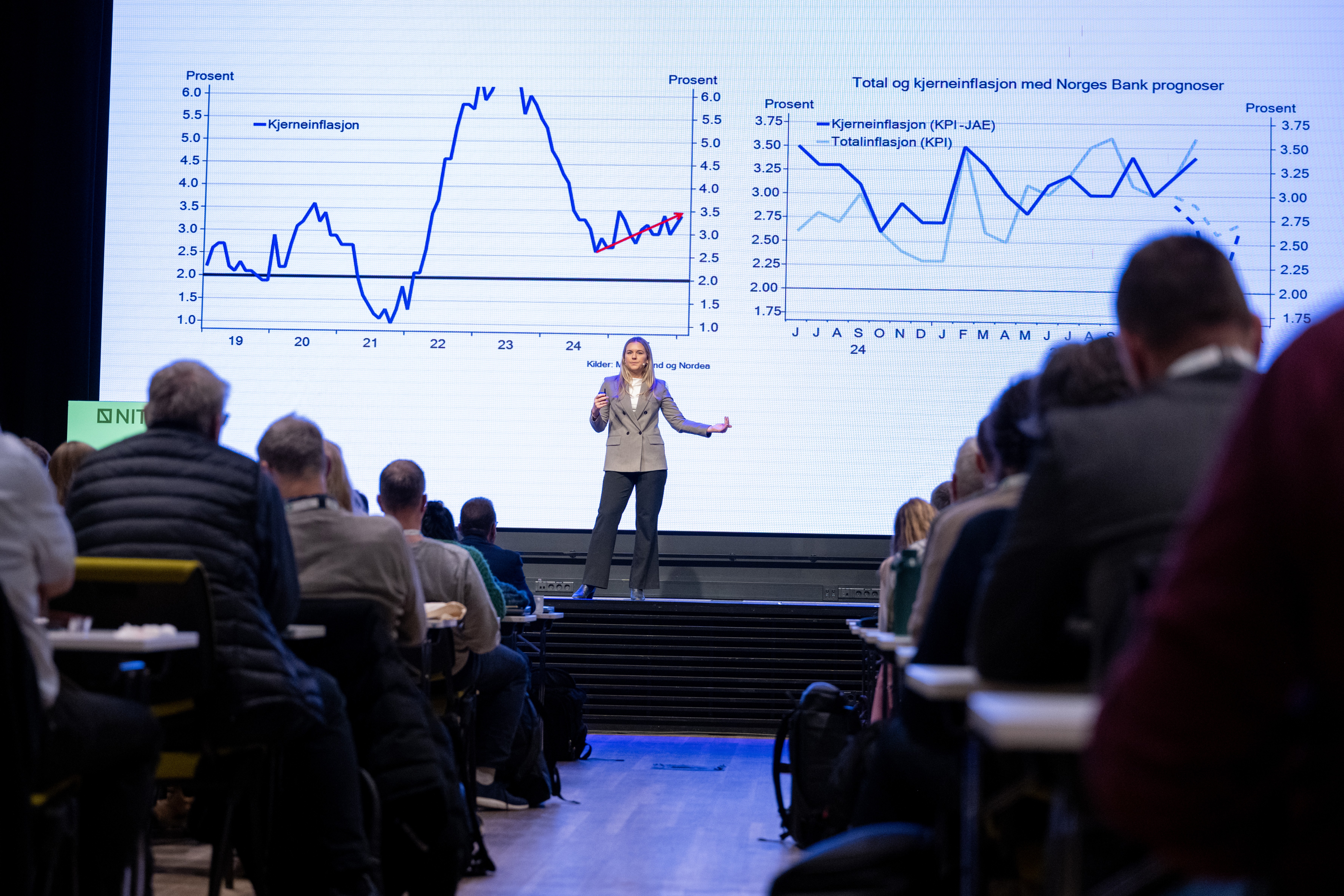 Lady showing graphs on screen stands on a stage. Credit: Bjarne Krogstad.