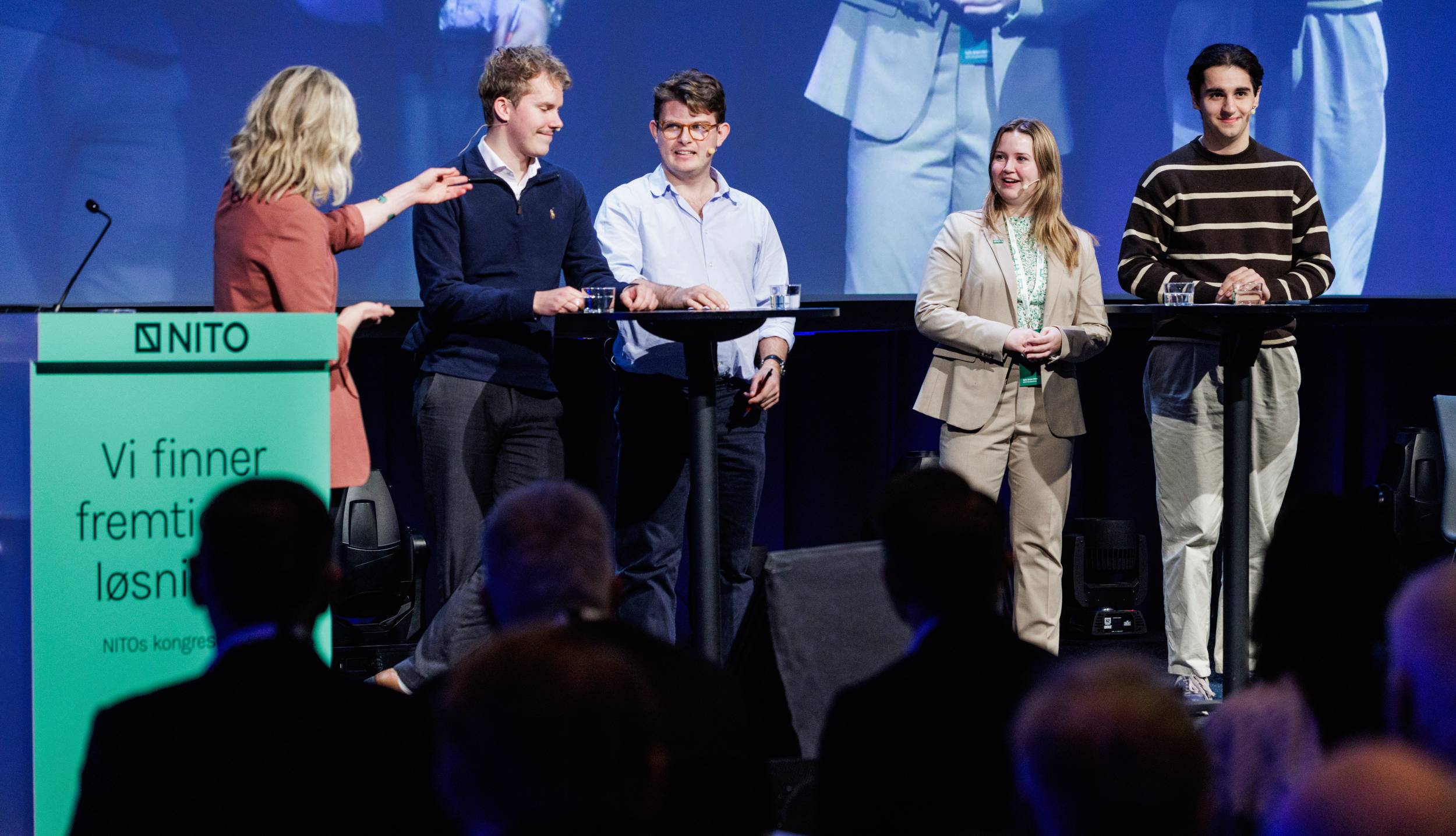 Panel debate on stage with four young people and one adult woman in front of an audience.