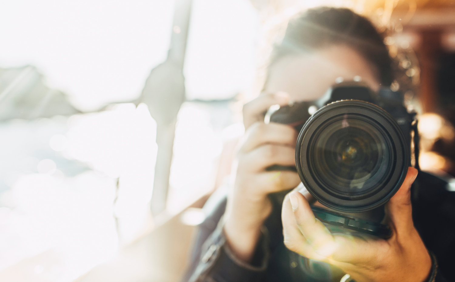 Kvinne med et kamera i forgrunnen. Bakgrunnen er uklar.