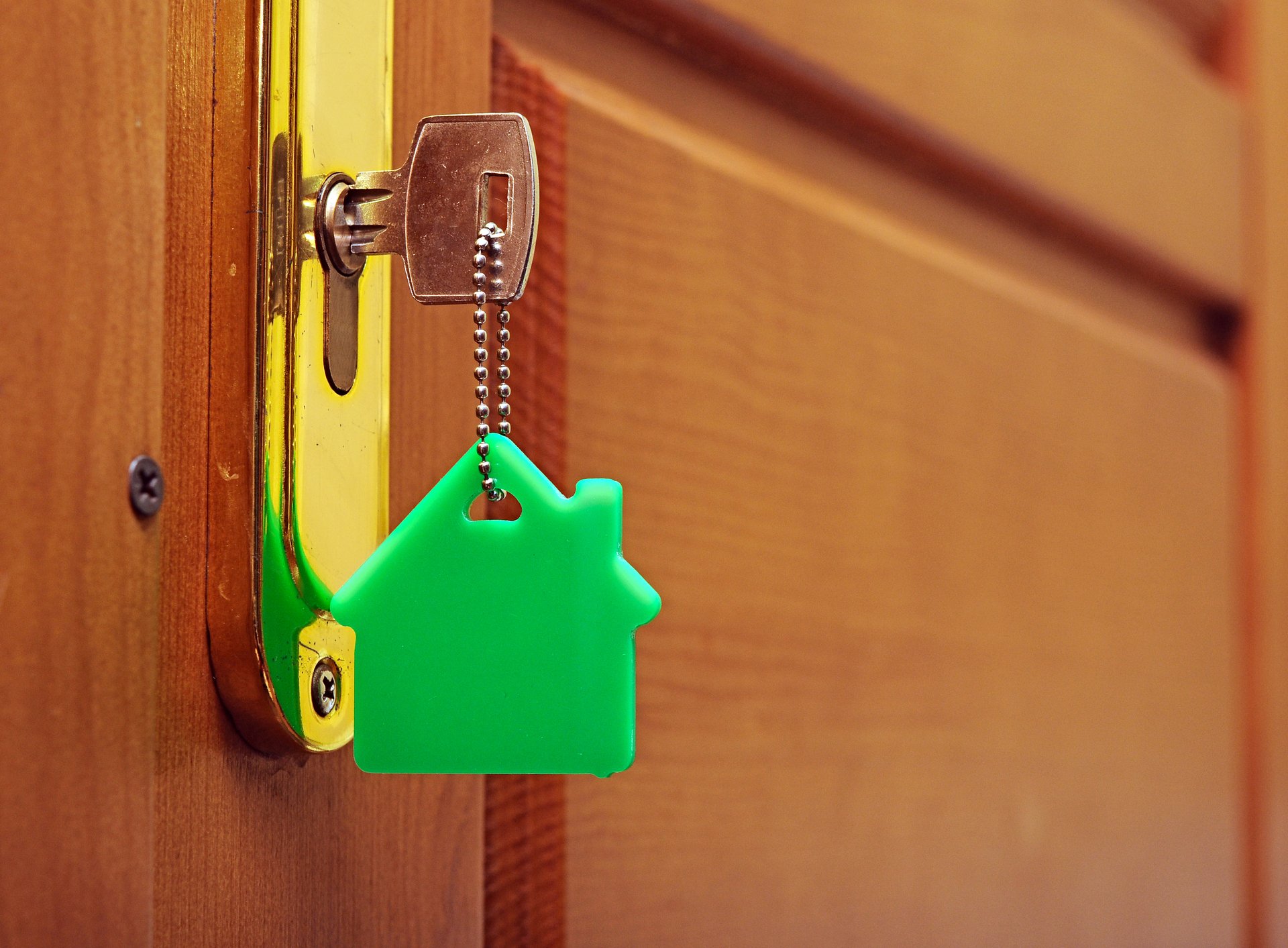 Et nøkkel i et nøkkelhull. Nøkken har en nøkkelring som er et grønt hus.