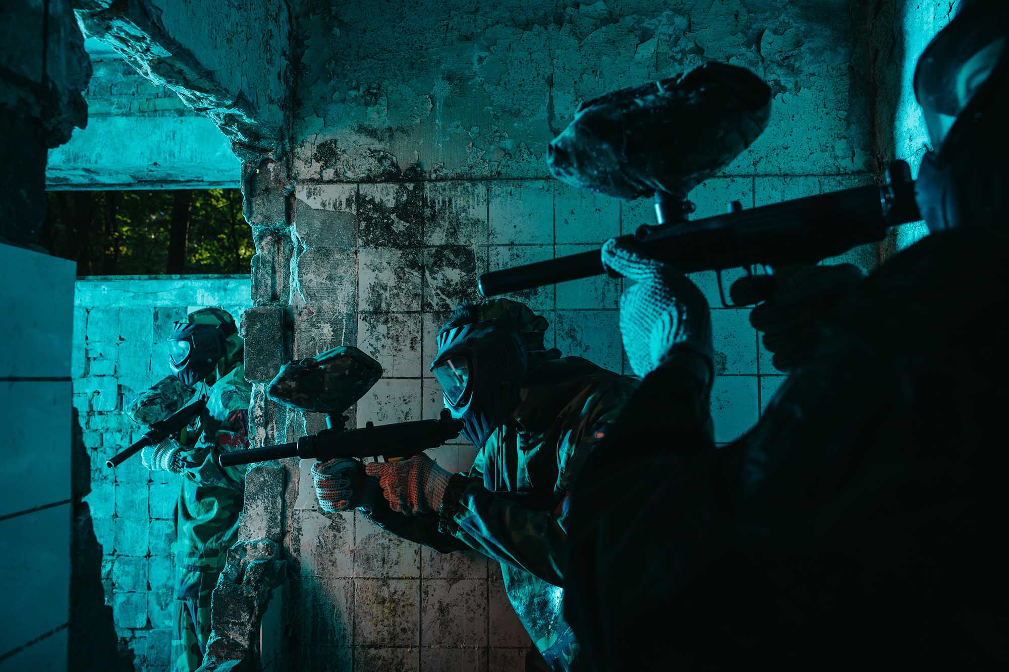 Tre personer som spille paintball innendørs 