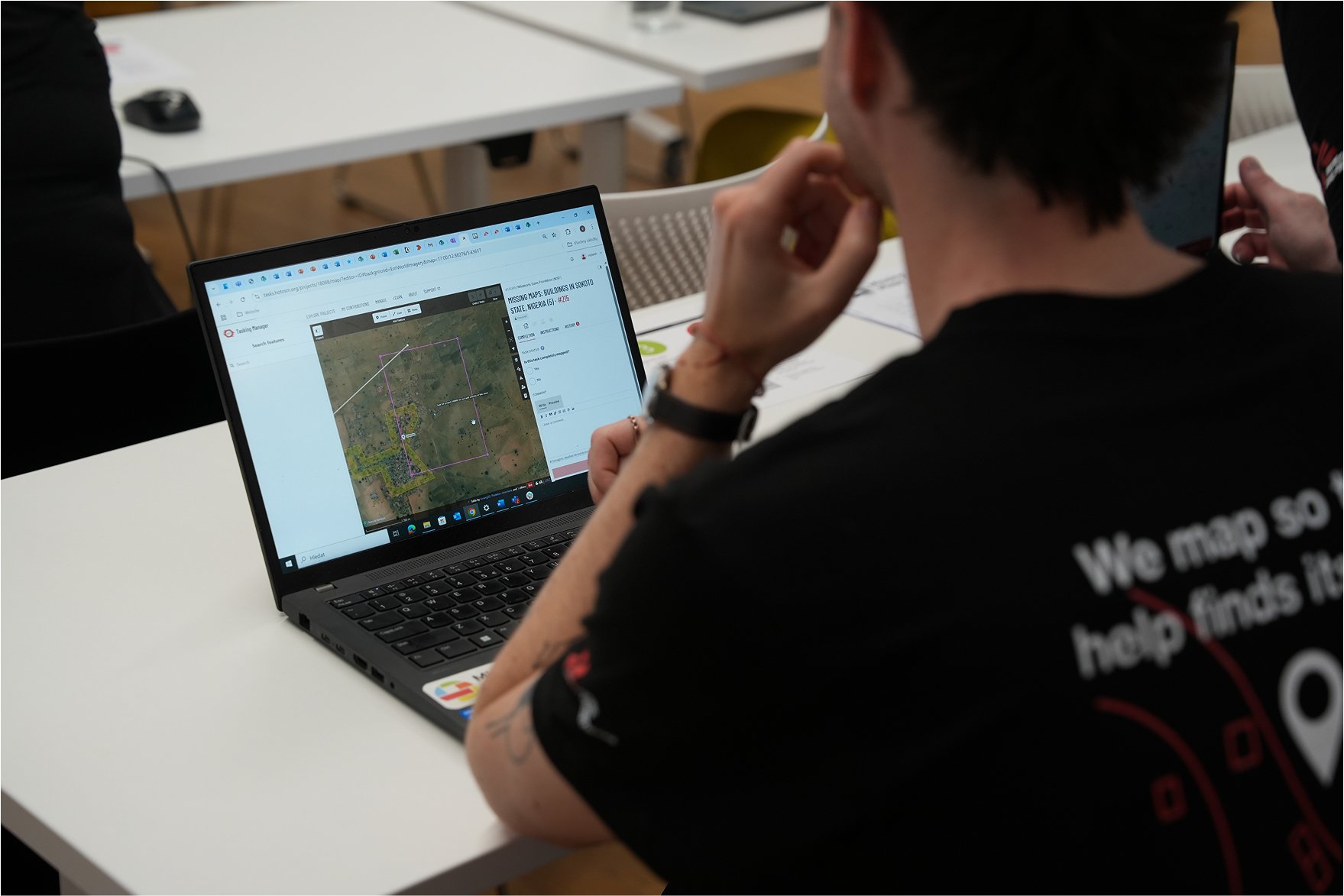 ung mann bakfra som ser på en laptop, med bilde av et kart