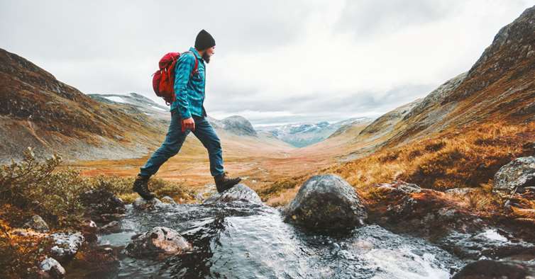 Mann på tur over en elv i fjellet: Foto: Shutterstock
