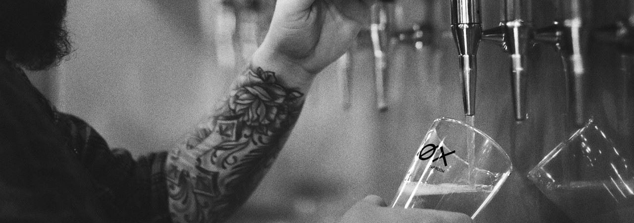 Foto av bartender som tapper øl i et gladd foto: ØXTapRoom