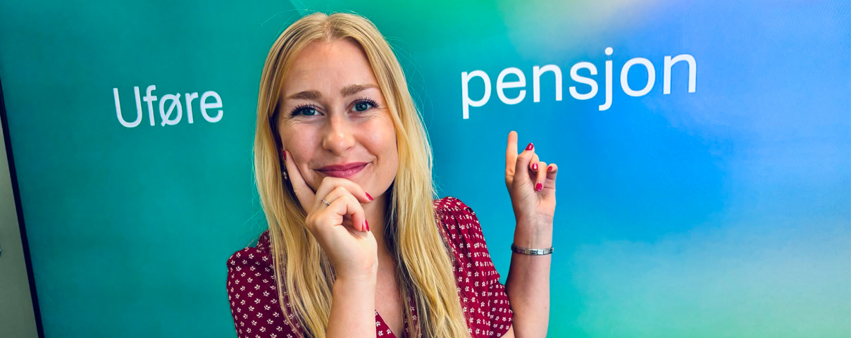 Inger Lise Sparboe Mørch peker opp på bakvegg med ordene uføre og pensjon