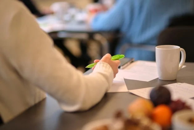 Hånd som holder i NITO-penn på møtebord