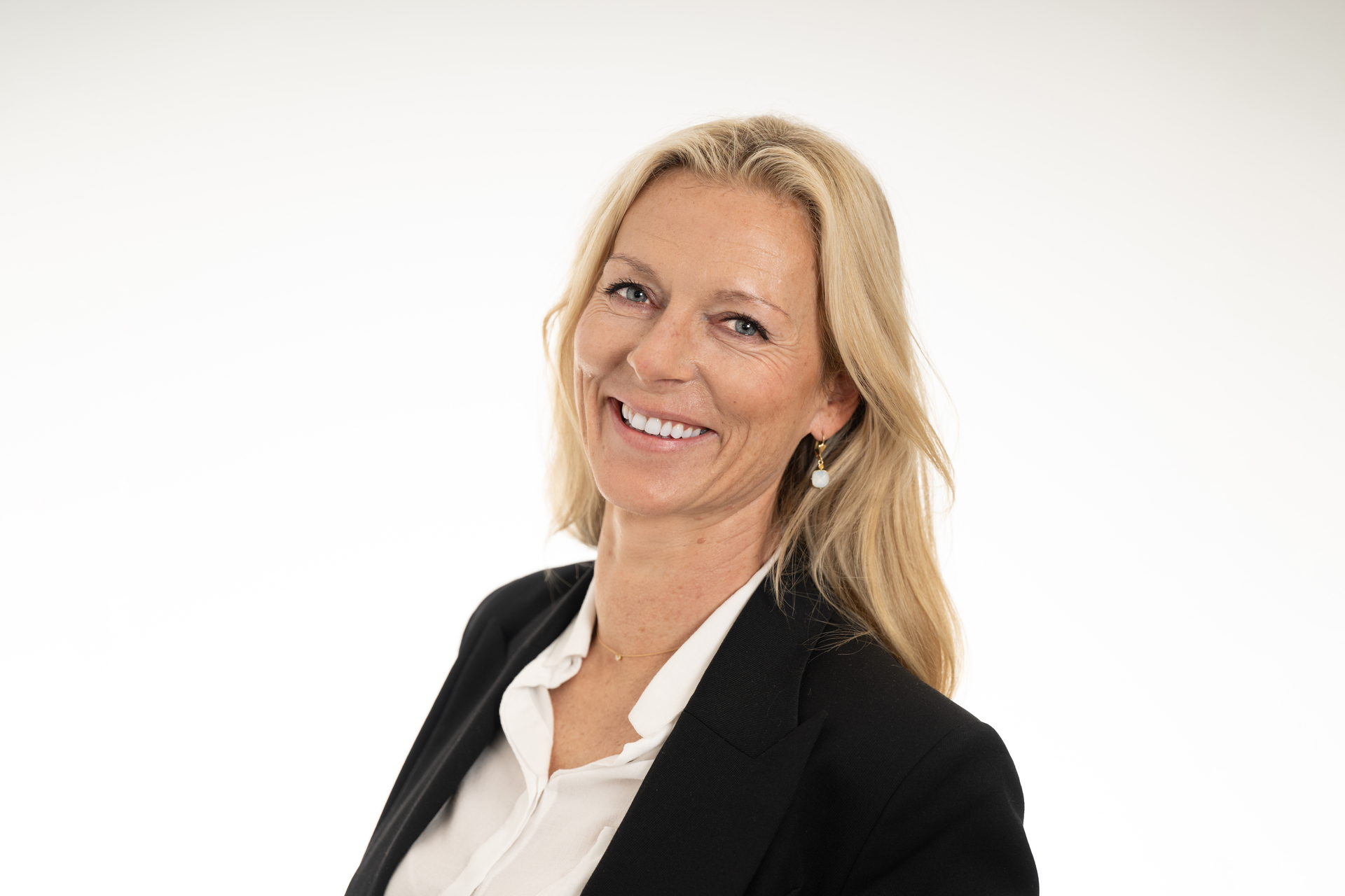 Smilende blond kvinne i hvit bluse og svart blazer