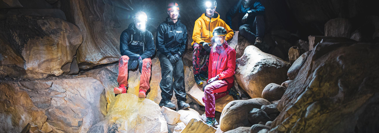 Fem mennesker med hodelykt og hjelm i en grotte