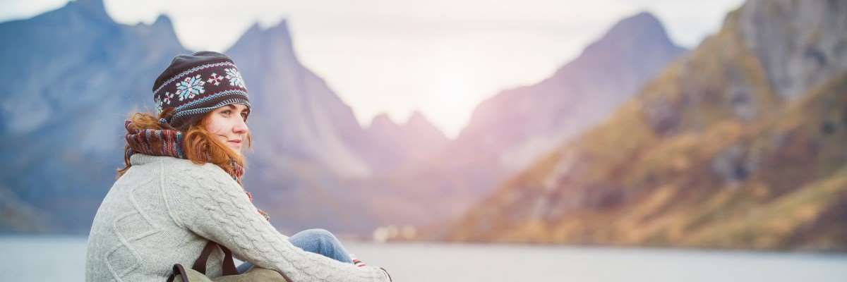 Kvinne sitter å ser utover fjellandskapet. Foto: Shutterstock