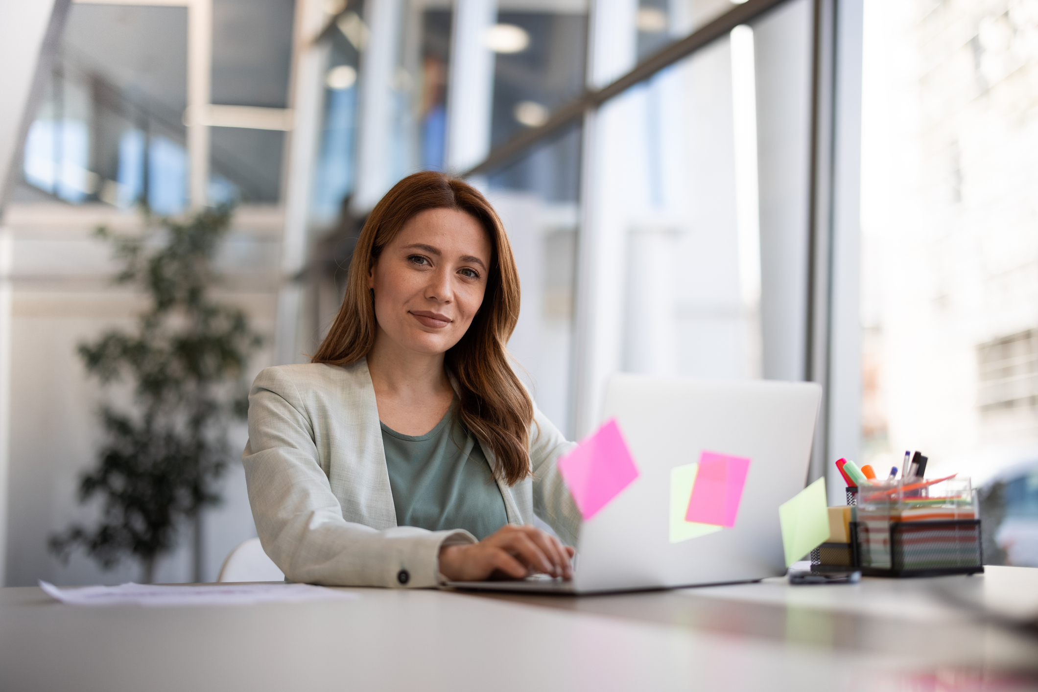 En kvinne som sitter på datamaskinen mens hun smiler.