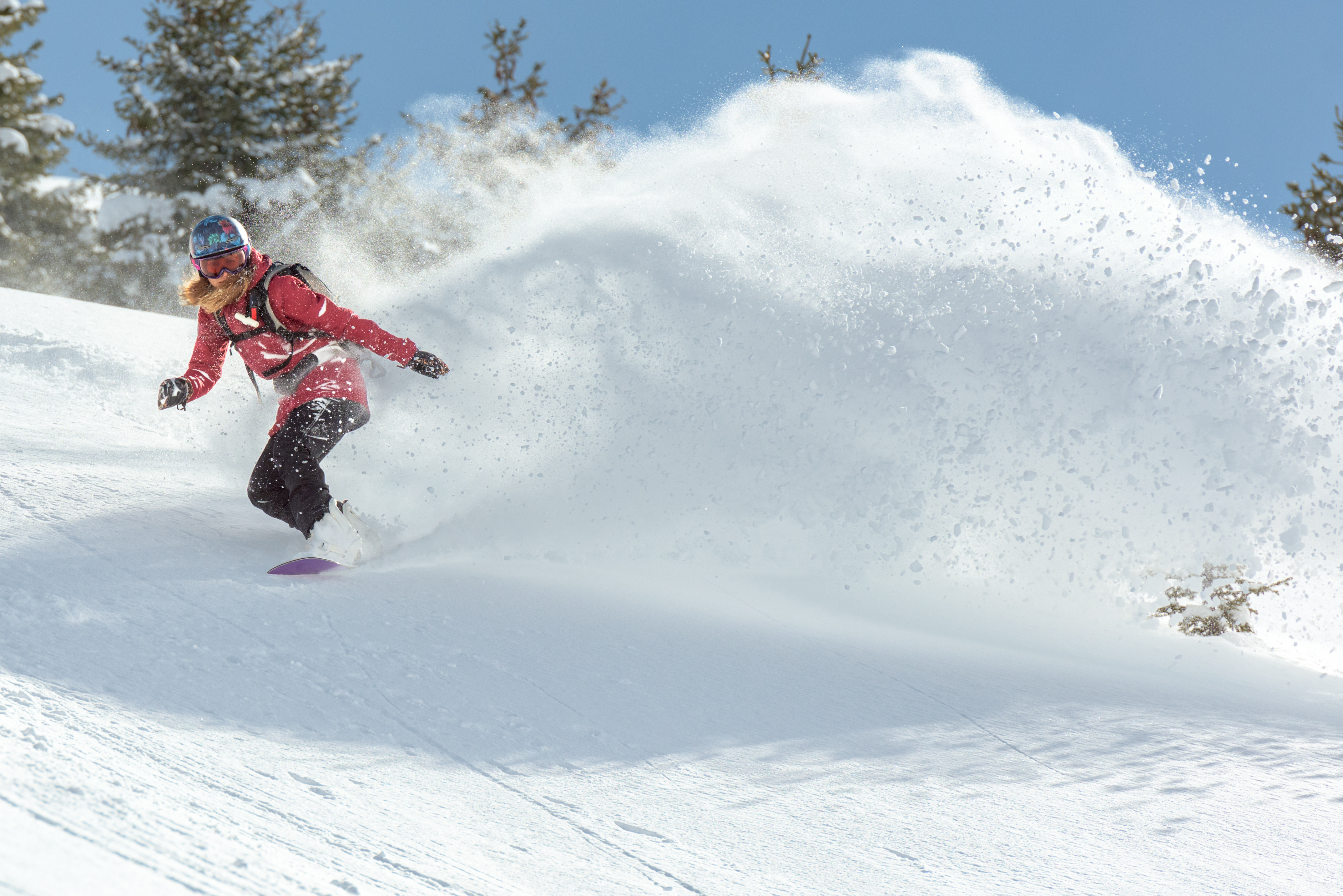 Kvinnelig snowboardkjører i fart. Snøen spruter. Kredit: Getty images