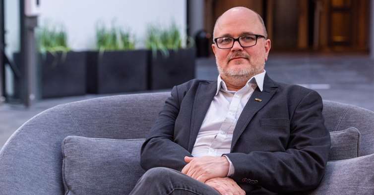 Kjell Ola Aamodt, leder av NITO Kommune, sitter i en grå sofa. 