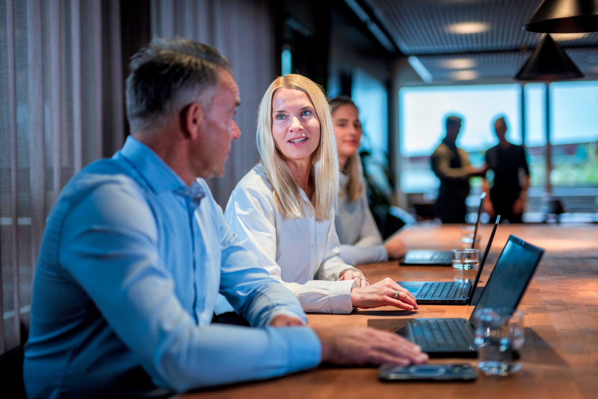 Ansatte i et møterom som diskuterer og samarbeider, med fokus på dialog og medbestemmelse i arbeidslivet.