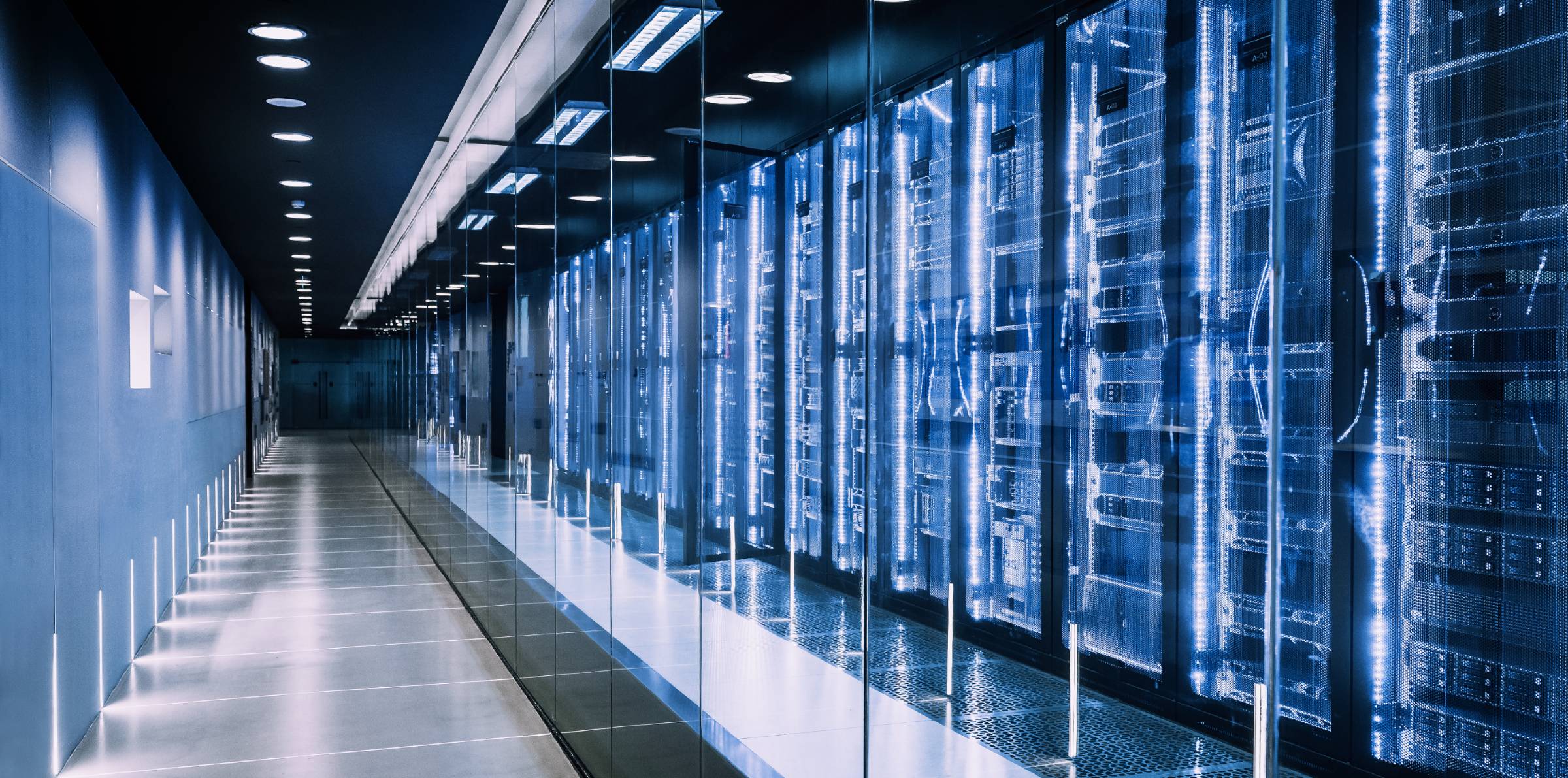 En lang, futuristisk korridor med glassvegger som viser rader av blålysende serverrack på rekke og rad.