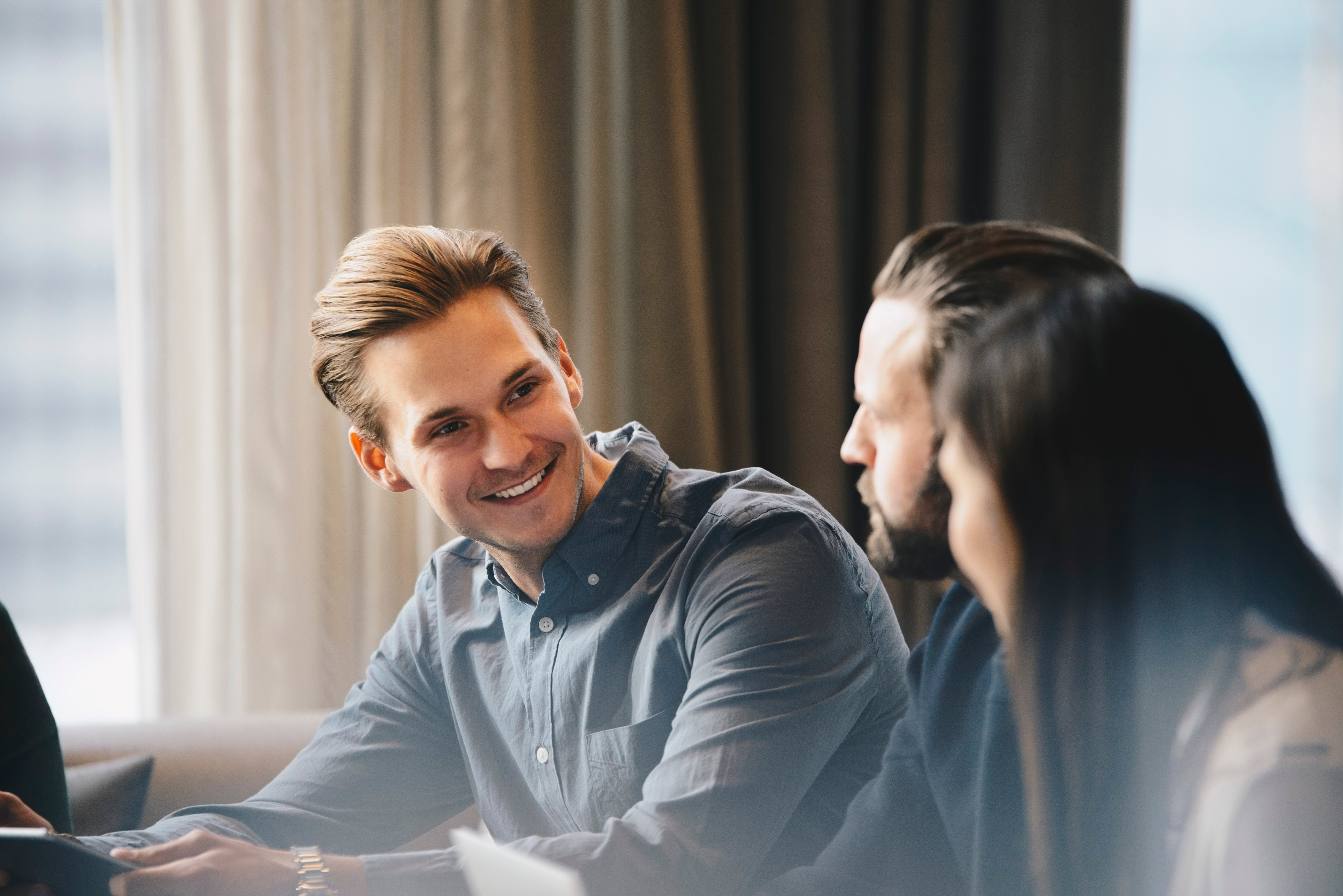 Mann smiler til to andre personer