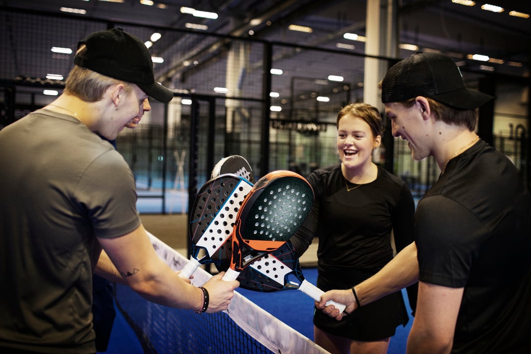 en gruppe venner står i ring med padelutstyr