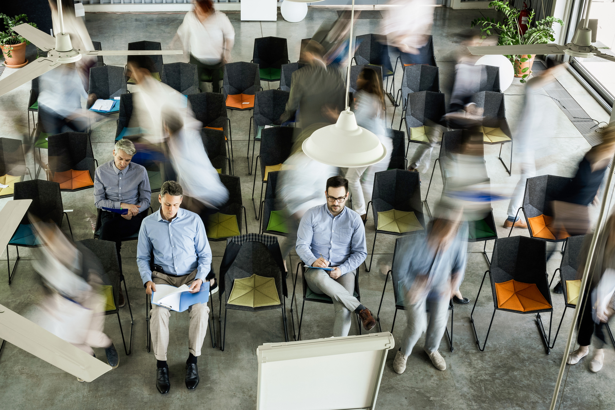 Personer som sitter og står i et konferanserom.