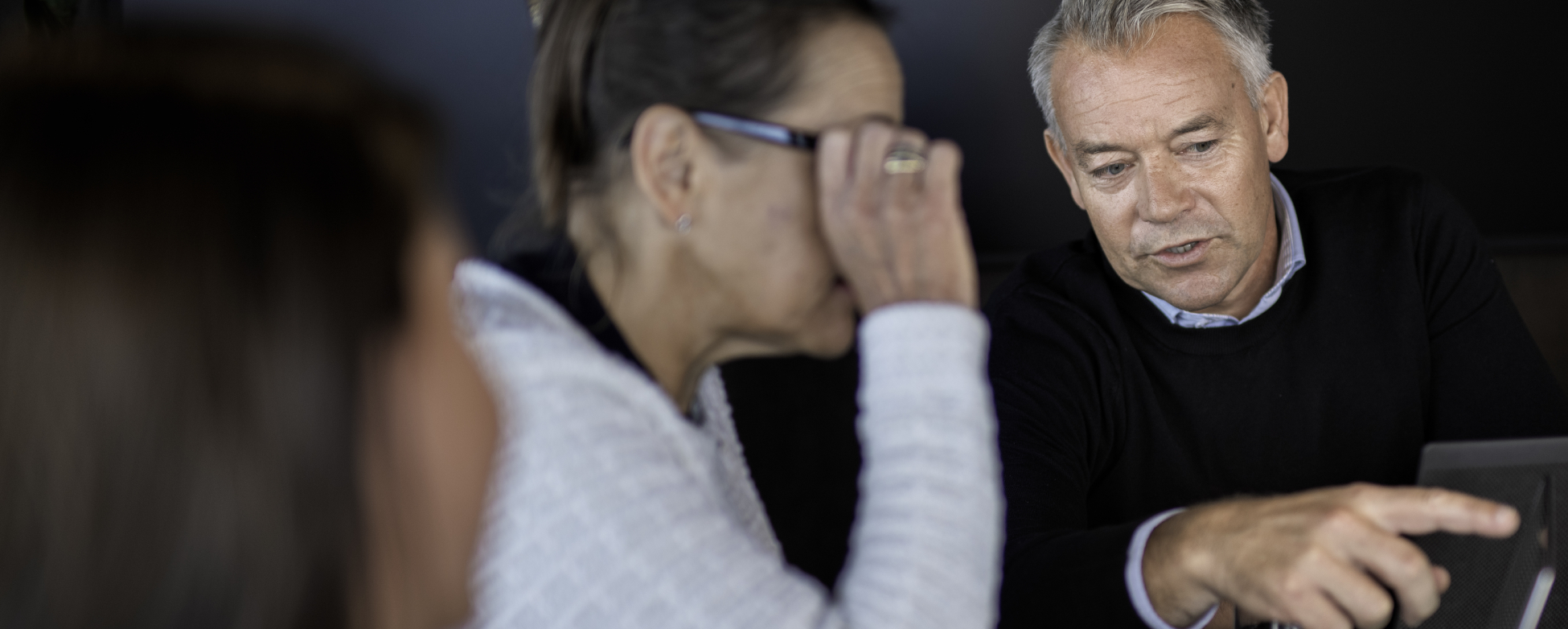 Tre personer som diskuterer, den ene personen peker på en laptop-skjerm.