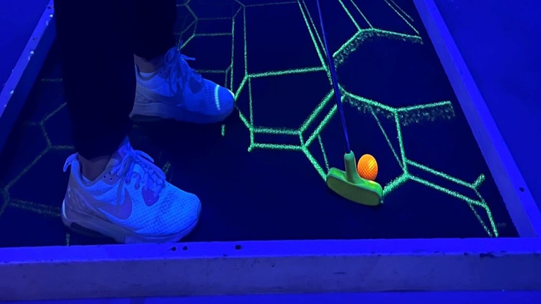 Person som spiller minigolf inne, neonfarger 