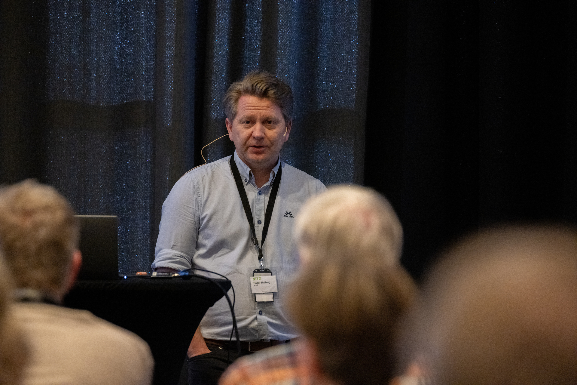 Mann med blå skjorte som holder innlegg på en konferanse