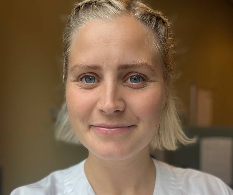 Smilende bioingeniør med lyst hår og hvit helsefrakk 