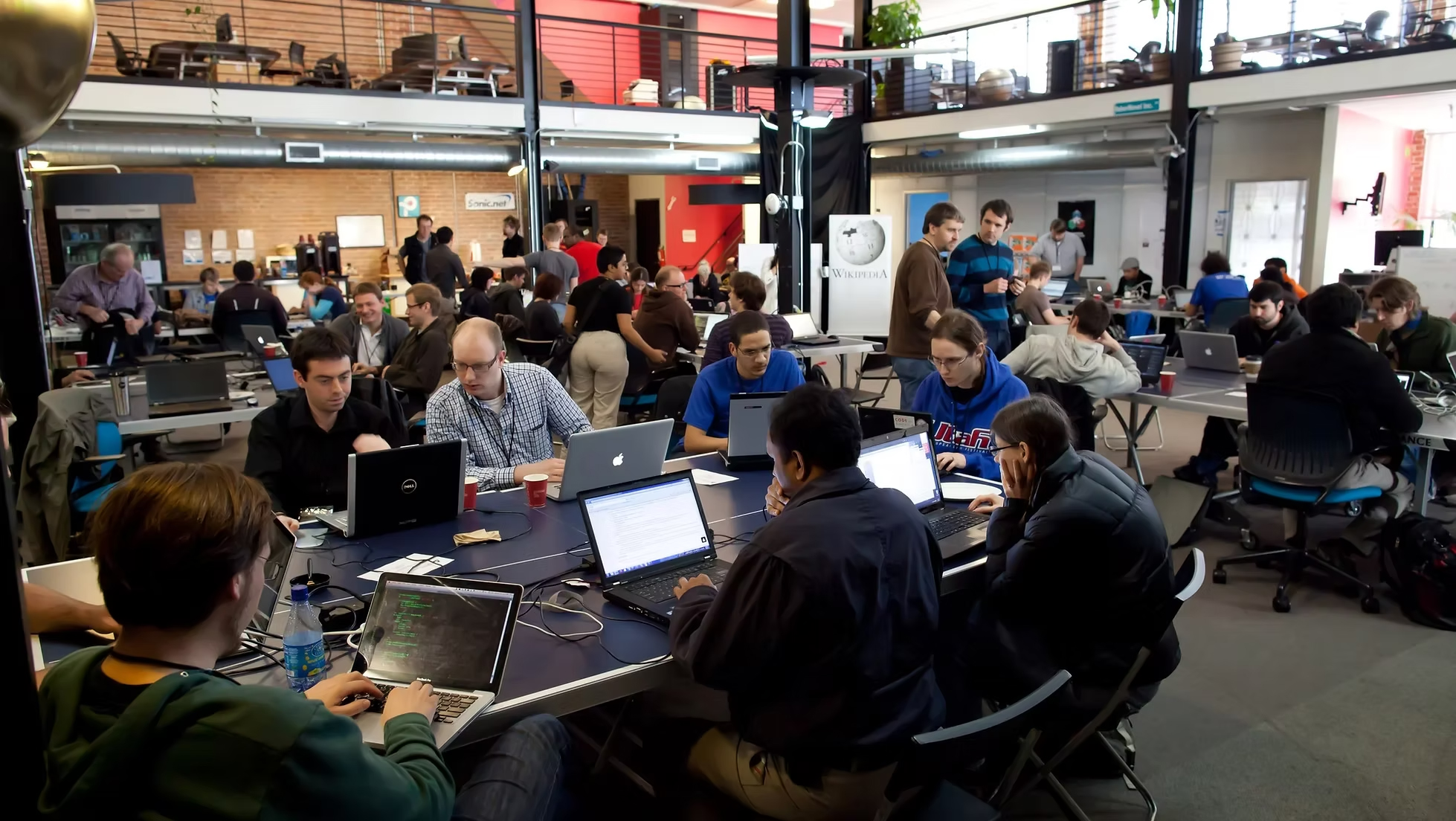 Many people in a room with each sim PC work intensively on solving tasks in a Hacketon