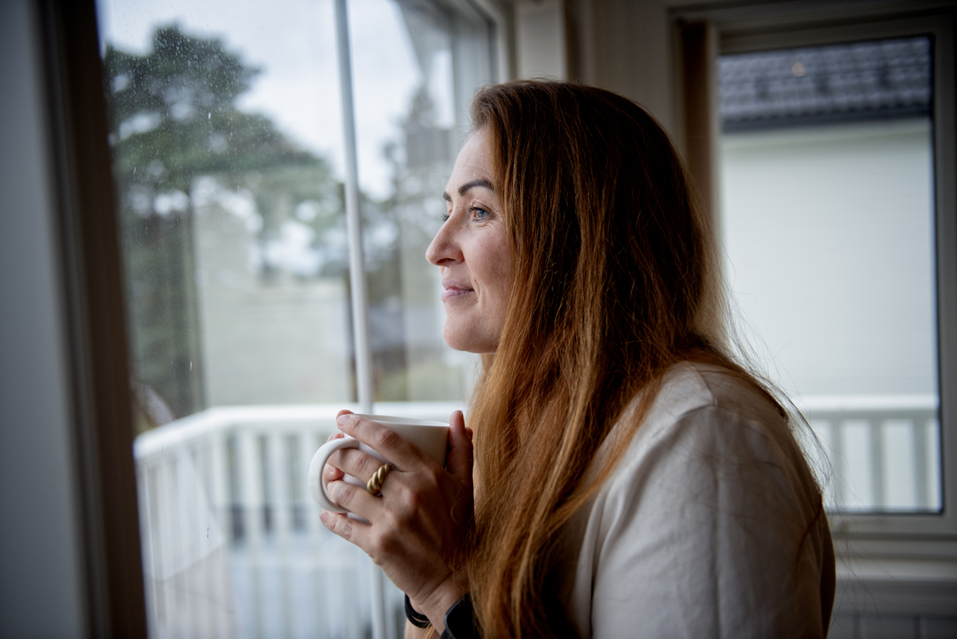 Illustrasjonsfoto: Kvinne ser ut av vindu.