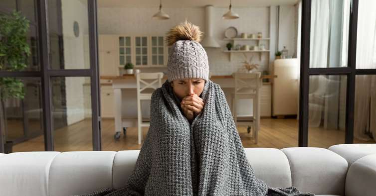 Bilde av en kvinne som sitter og fryser hjemme.
