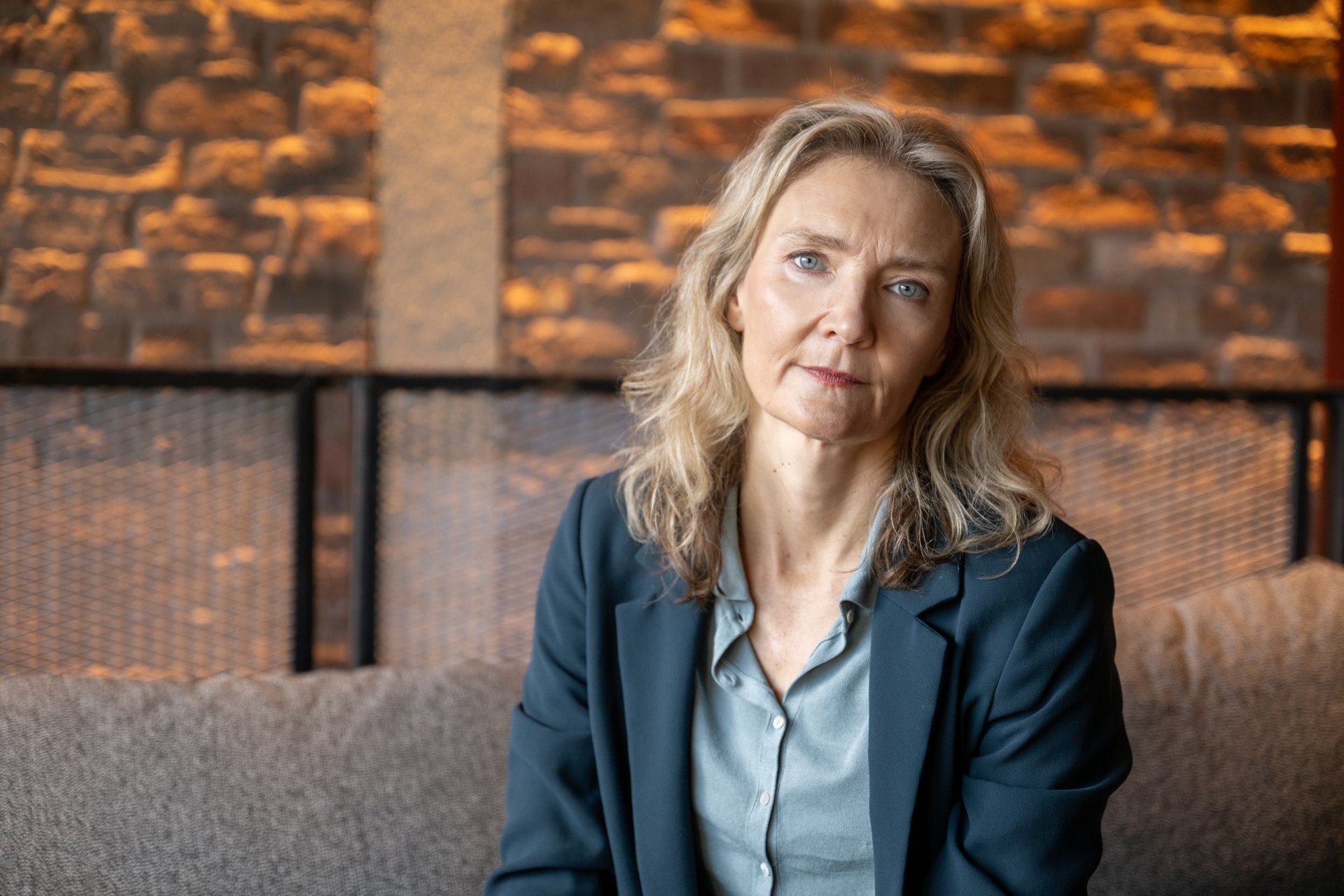 Blonde lady in grey blouse and dark blue jacket