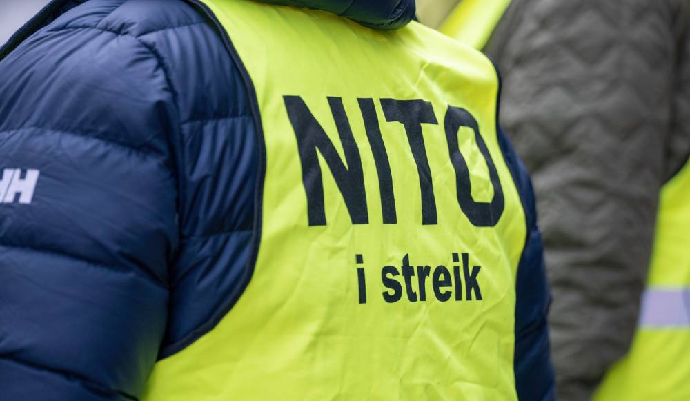Person i gul refleksvest med teksten «NITO i streik» trykt på ryggen.