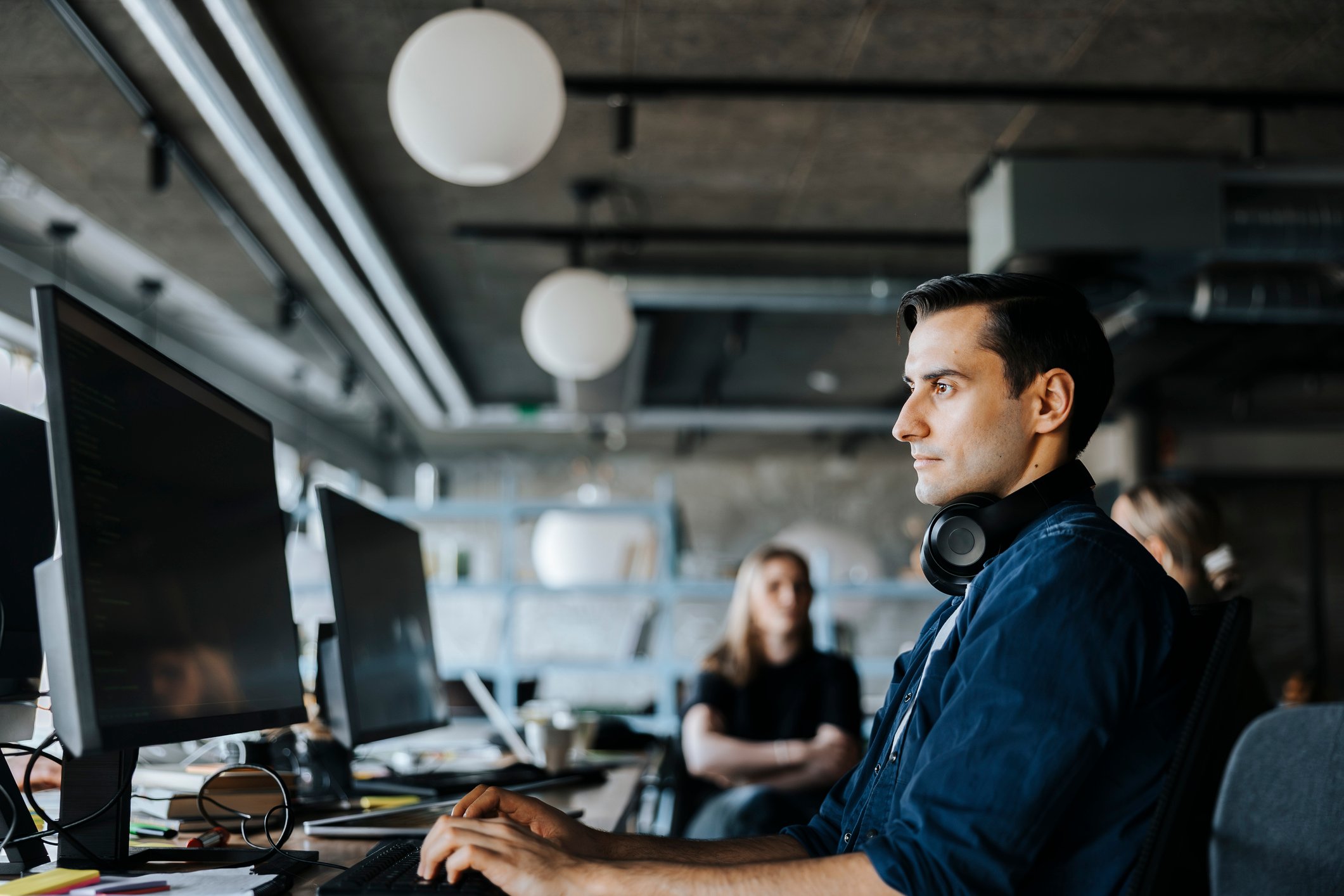Utvikler med hodetelefoner foran skjerm