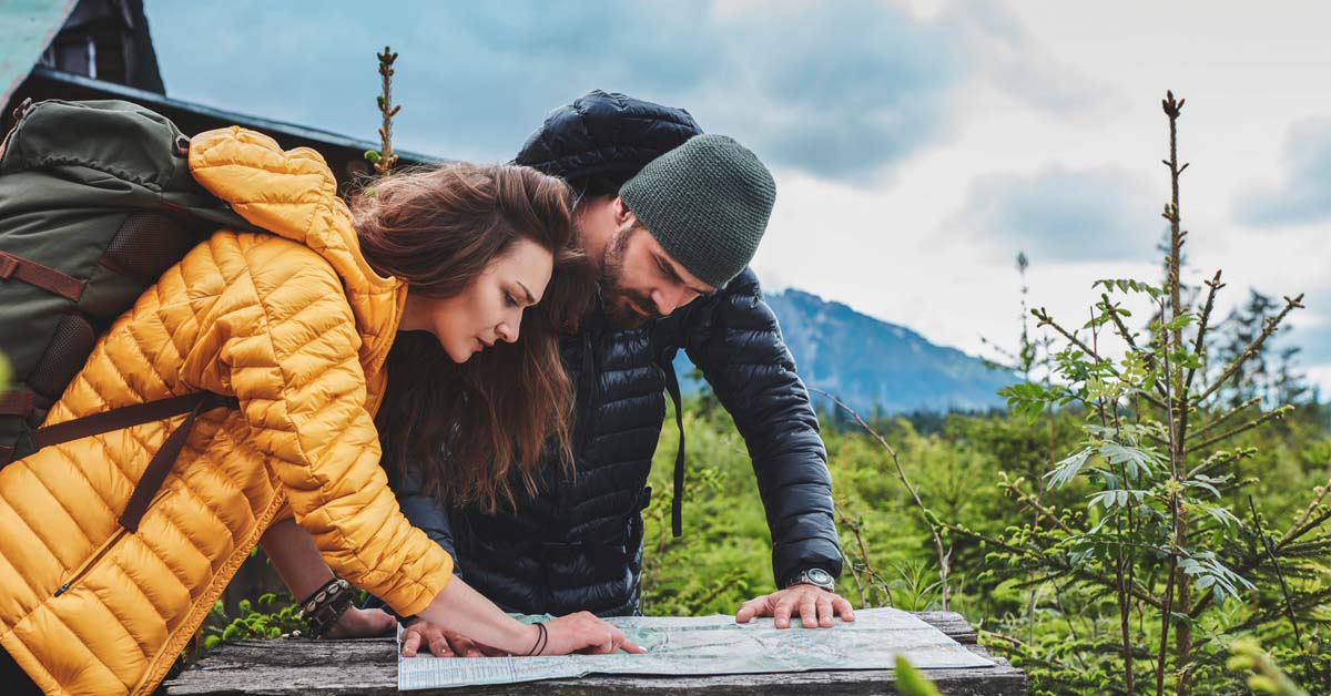 Man and woman on a mountain hike studying the map