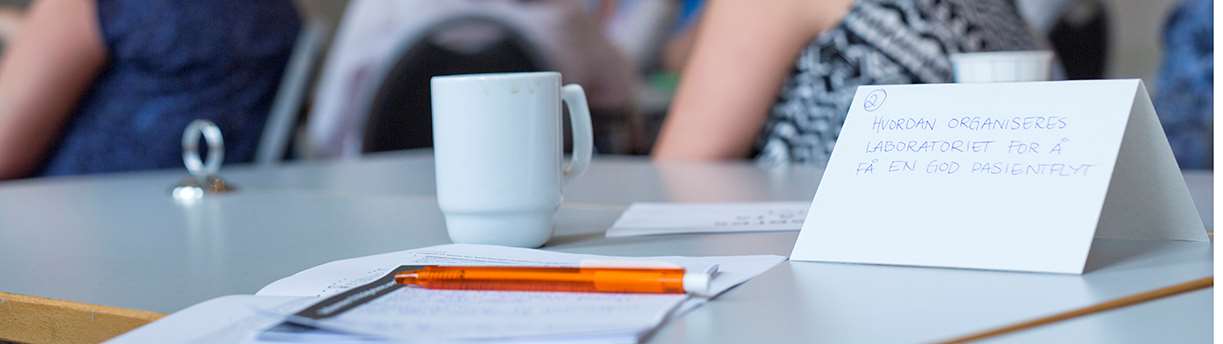 Papir og kaffekopp i et møterom