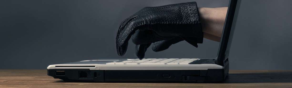 PC, fingre ut av skjerm med svarte hansker. Foto: Colourbox