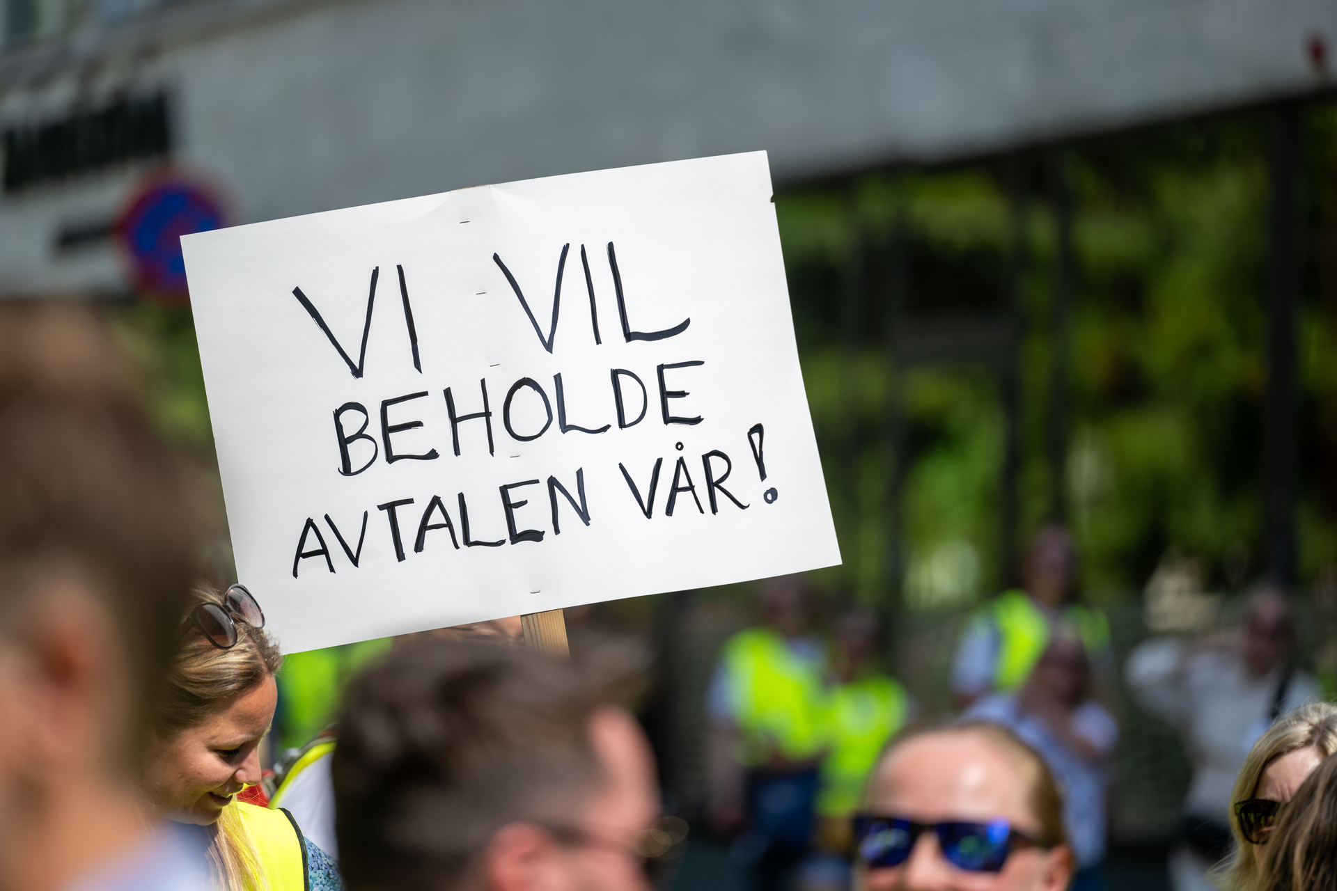 Demonstranter holder opp et skilt med teksten "VI VIL BEHOLDE AVTALEN VÅR!", som illustrerer Akademikernes streik i 2024 for å bevare hovedtariffavtalen i staten.