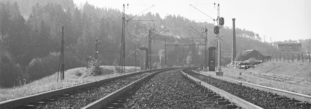 svart hvitt bilde av togskinner med skilt med signalskilt om 4 km til 
