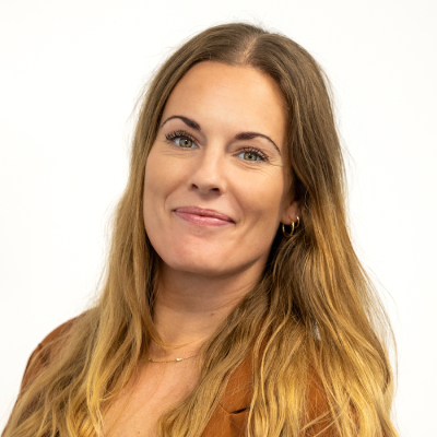 Portrett av smilende kvinne med langt, mørkeblondt hår