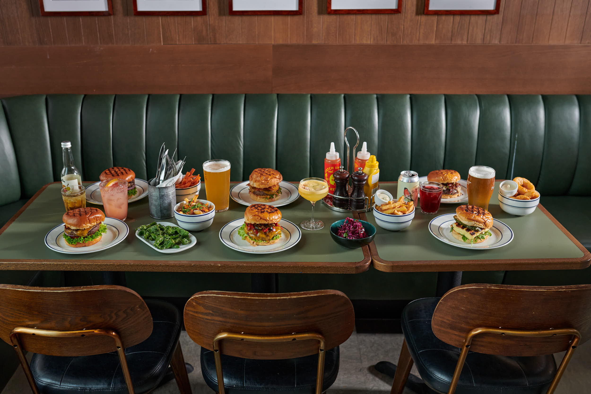 bilde av et bord fullt av hamburgere, pommes frites og alkoholfri drikke.